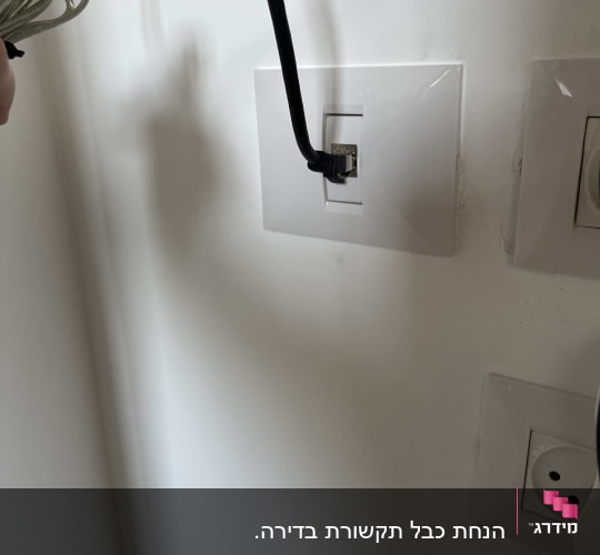 שקע רשת לבן בקיר עם כבל רשת שחור מחובר